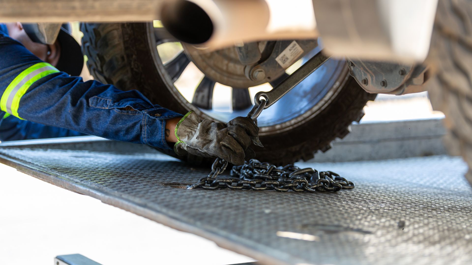 Worker securing vehicle wheel with chain on metallic surface