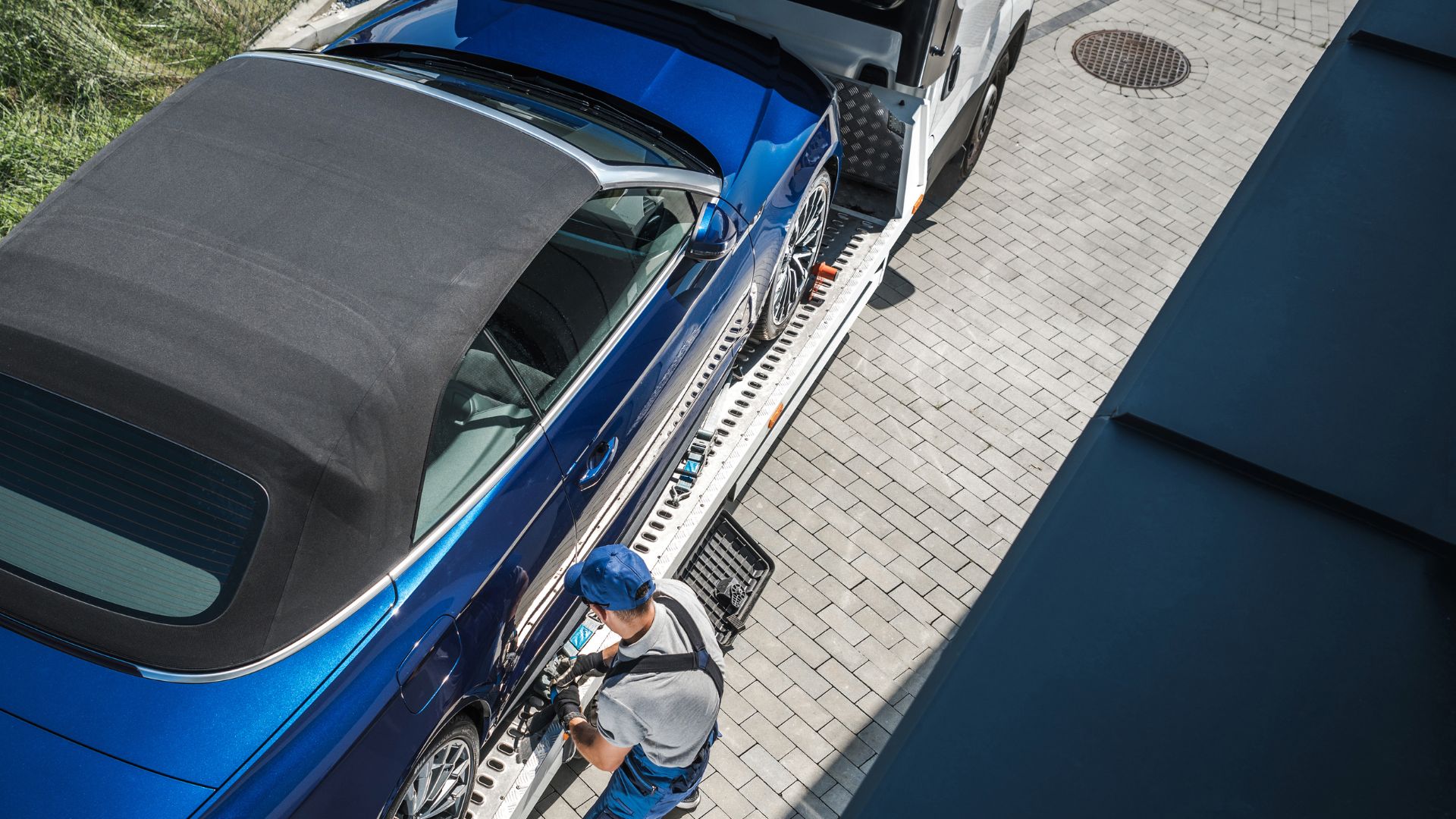 Blue car being loaded onto a transportation trailer from above