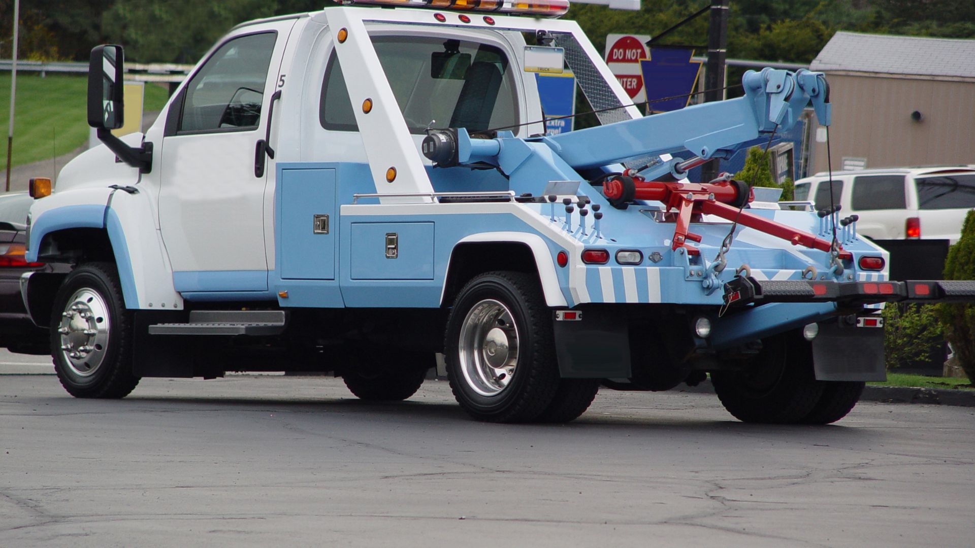 Blue and white tow truck with hydraulic arm parked in lot