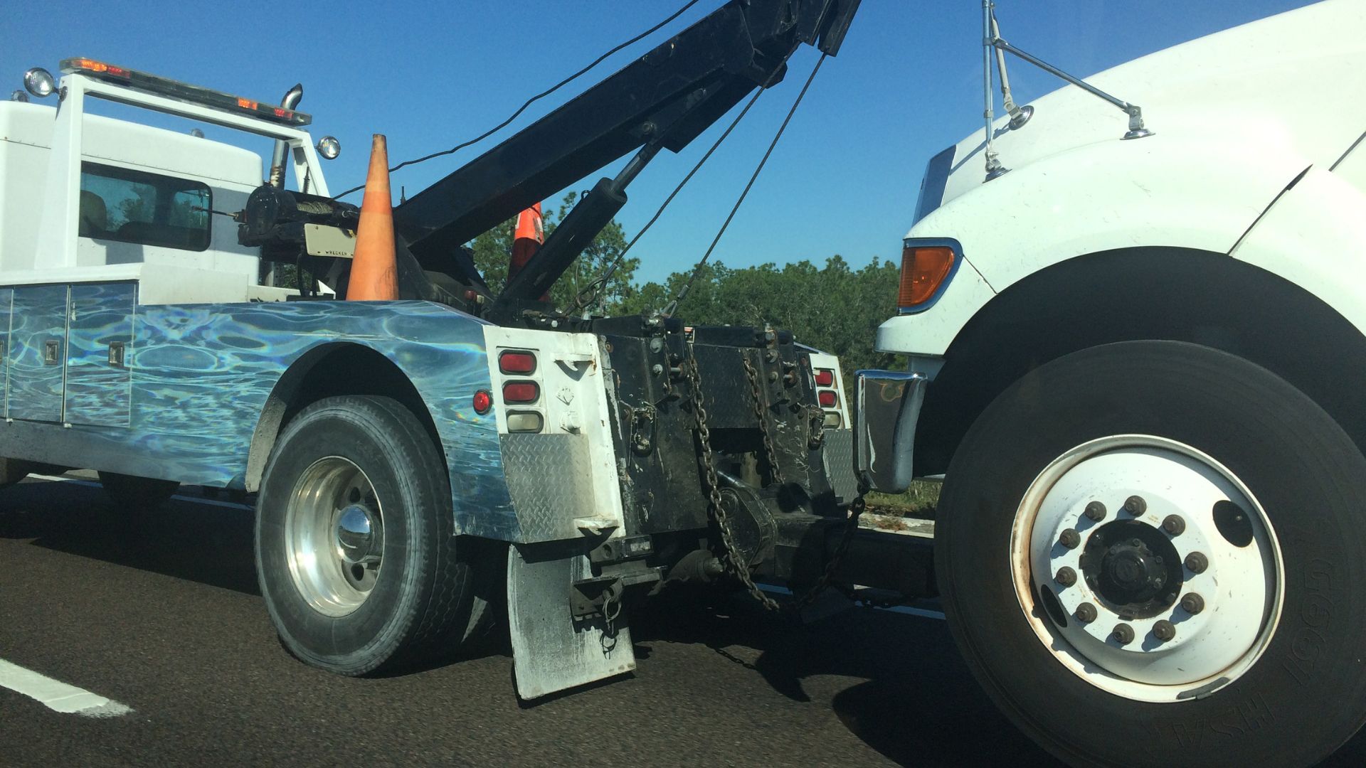 White tow truck with hydraulic crane and safety cone on roadside